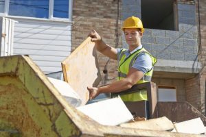 builder throwing wood into a skip bin